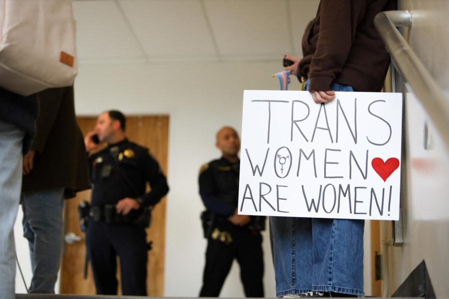 SF State student, Mars Peer (he/him), holds up a sign inside of SF State’s HSS building in protest of SF State’s Turning Point USA Chapter event “Saving Women’s Sport with Riley Gaines” on Thursday, April 6, 2023. Peer came to show solidarity for trans people and was outraged to see SF State hold an event of transphobic nature. (Gina Castro / Golden Gate Xpress)