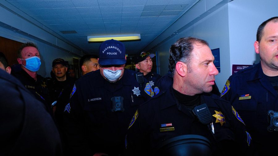 Campus police officers along with officers from SFPD form a barricade outside of the room where Riley Gaines stayed after the conclusion of the event at SF State on Thursday, April 6, 2023. SFPD officers were called to assist with escorting Gaines out of the building. (Miguel Francesco Carrion / Golden Gate Xpress) 