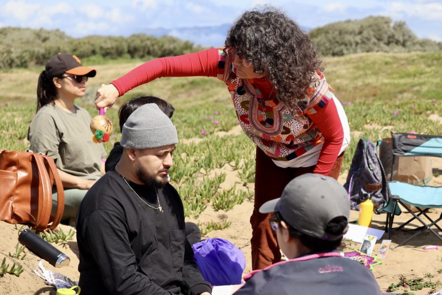 Yvette Mari Robles, curandera and SF State alum, uses a rattle to break an attendees aura to receive energy work to support their following journey to connect with the land at Fort Funston in San Francisco, Calif., on Saturday May 6, 2023. (Adriana Hernandez / Golden Gate Xpress)