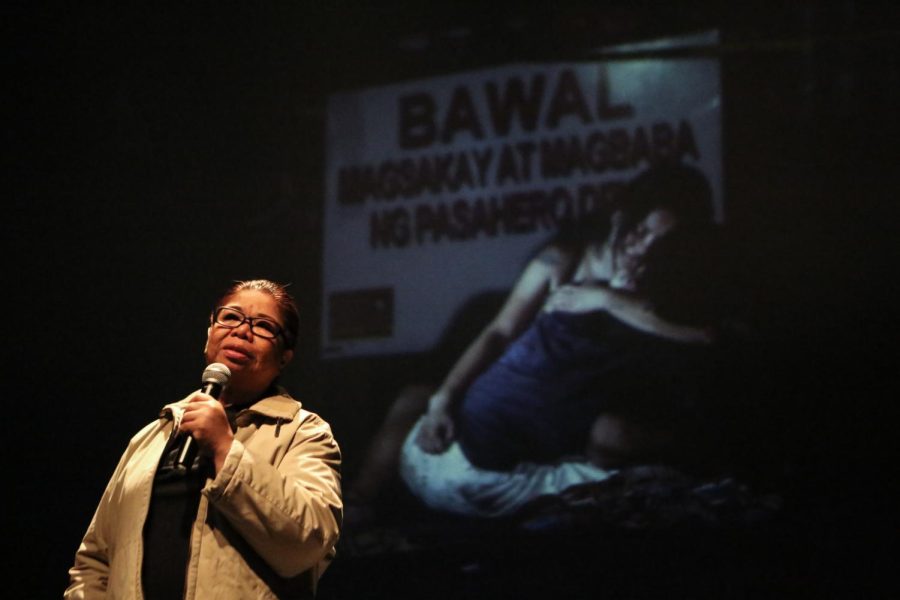 Mae Paner delivers a monologue during a performance of her play Tao Po before it was adapted into a film. The photo behind Paner shows Jennilyn Olayres holding her partner Michael Siaron after Siaron was extrajudicially killed during President Duterte’s drug war. (Courtesy of Mae Paner)