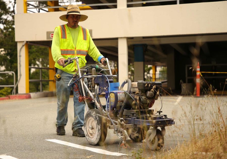 Sal Leon, a private contractor, re-paints the lines of parking lot 19 at SF State on June 15, 2023. (Tam Vu / Golden Gate Xpress)