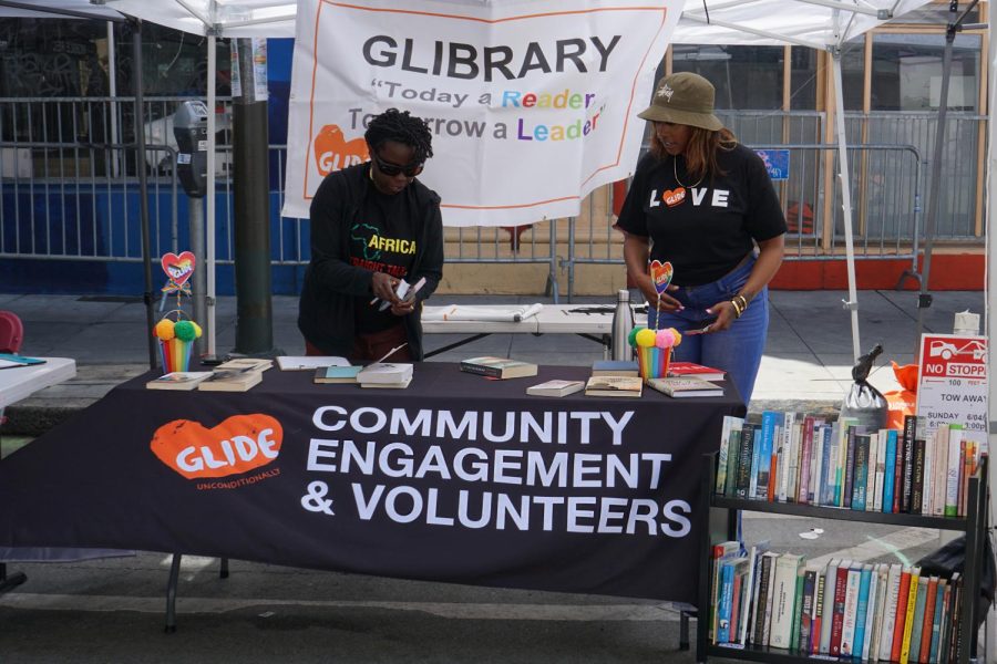 Two volunteers for GLIDE set up their booth in preparation for Sunday Streets in the Tenderloin neighborhood in San Francisco, Calif., on June 4, 2023. (Bryan Chavez / Golden Gate Xpress)