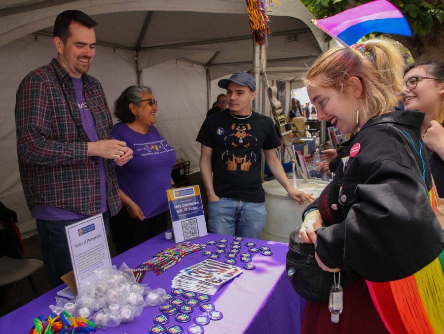 Dayne Wahl (L), Associate Director for Undergraduate Recruitment, shares a laugh with a person who was interested in the booth at SF Pride on June 24, 2023. (Tam Vu / Golden Gate Xpress)