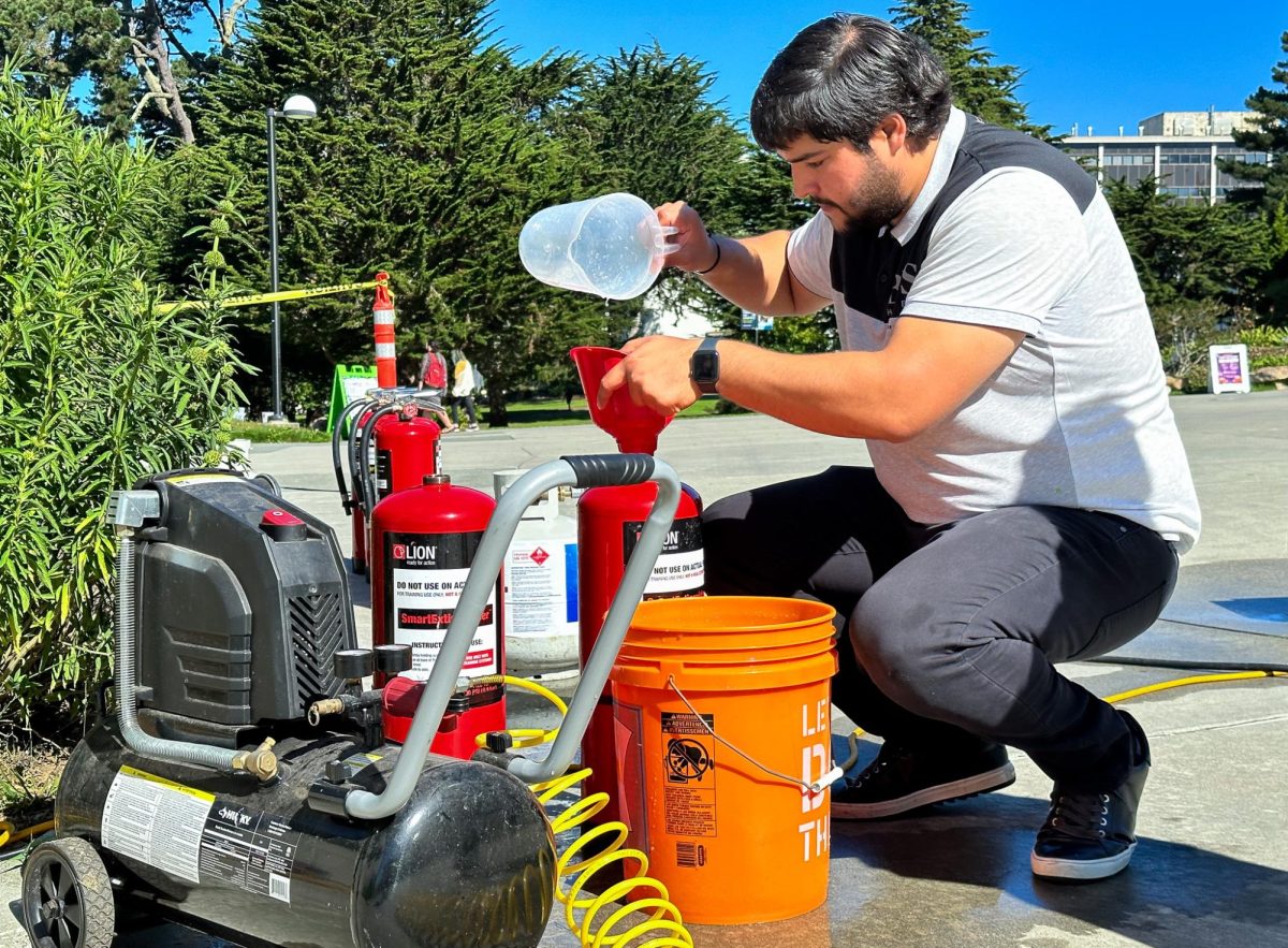 A volunteer student depressurized the fire extinguisher,  proceeded  to add more water and replace a new  valve stem to recharge and re-pressurize it again after one use, on Oct. 17, 2023.(Feven Mamo  / Golden Gate Xpress)