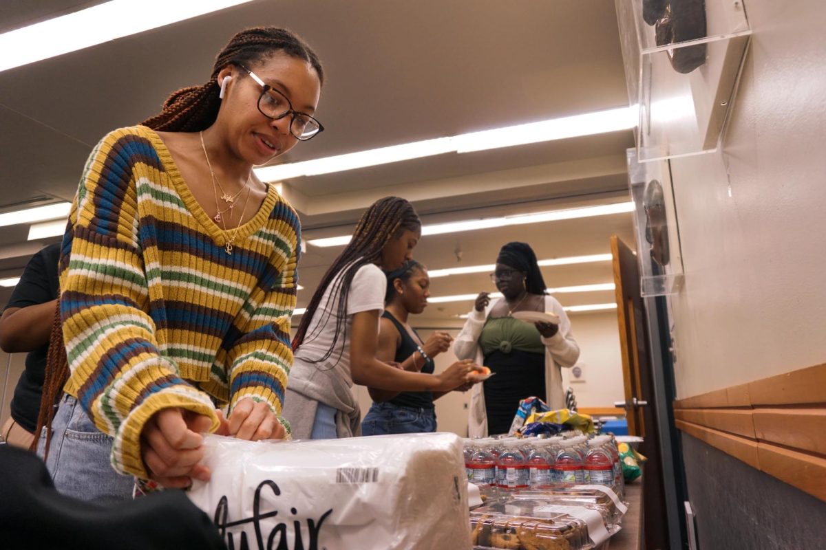 Nyla Sanders grabs some food during Black Residents United in Housings Guess whos Back event in the Cesar Chavez building on Thu, Oct. 5, 2023. (Bryan Chavez / Golden Gate Xpress)
