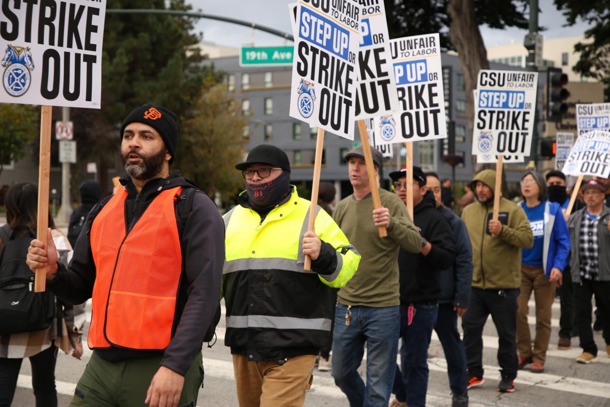 Teamsters union members hold up their picket signs and chant as they cross the street to block off 19th Street and Holloway in protest of unfair bargaining in their contracts at SFSU on Nov. 14, 2023. (Tam Vu / Golden Gate Xpress)
