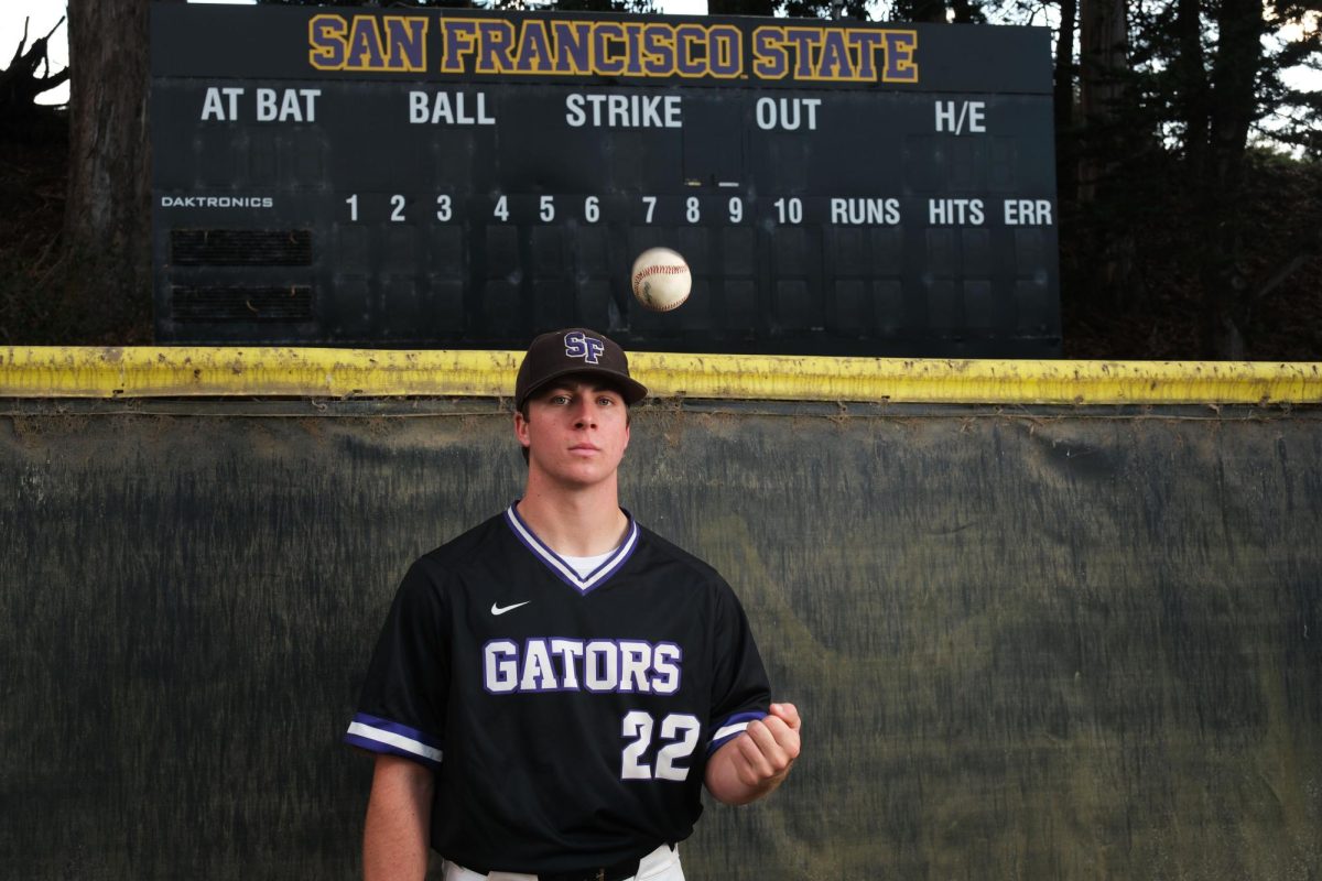 Nathan Shinn, a left-handed pitcher for the SFSU baseball team, poses for a portrait near the outfield wall in Maloney Field on Thursday, Nov. 16, 2023. (Andrew Fogel / Golden Gate Xpress) 