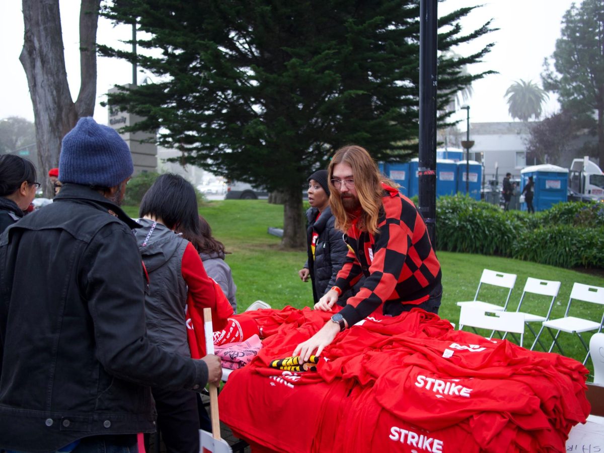 Student and faculty volunteers giving out red-colored t-shirts to CFA picket line participants at 19th and Holloway on Tuesday, Dec. 5, 2023. (Dmitry Berdnikov / Special for Golden Gate Xpress)