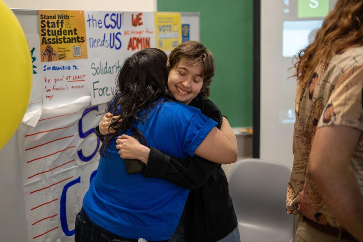 Volunteer organizer Ashley See (left) and San Francisco State University student assistant Becca Wilson (right) embrace following the results of the California State University Student Assistant union election via electronic ballot at a watch party in Burk Hall on Friday, Feb. 23, 2024. (Sean Young / Golden Gate Xpress)