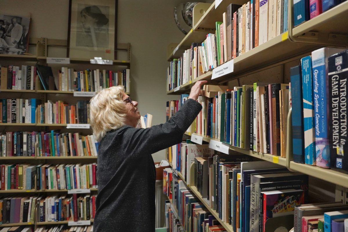 Barbara Loomis shelves books in the Friends Used Book & Media Store on Feb. 7, 2024. (Neal Wong / Golden Gate Xpress)