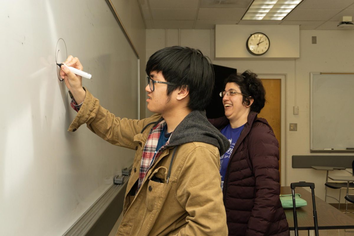 Ren Nocon (center), a cinema student, draws on the whiteboard with his eyes closed as part of Experimental College teacher Masha Aleskovksi’s (right) lesson plan for Diversibility in Burk Hall on Feb. 13, 2024. (Dan Hernandez / Golden Gate Xpress)