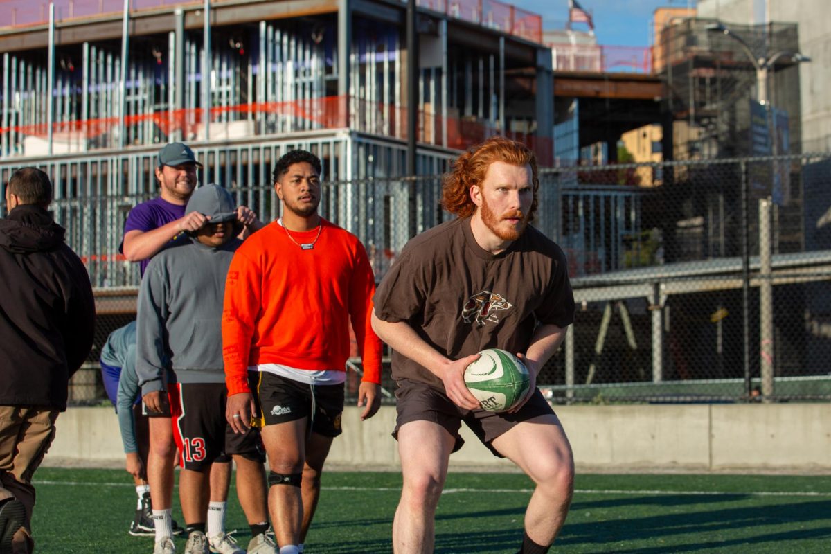 Jaden Cook (center right) holds a rugby ball during a SFSU men’s rugby team practice  on Tuesday on the field outside Mashouf Wellness Center. (Dan Hernandez / Golden Gate Xpress)