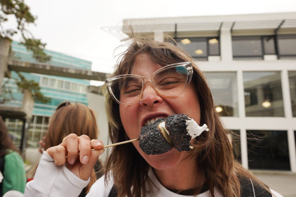 Talia Rubinstein, a student, bites into marshmallows at Malcolm X Plaza on March 20, 2024. (Neal Wong / Golden Gate Xpress)