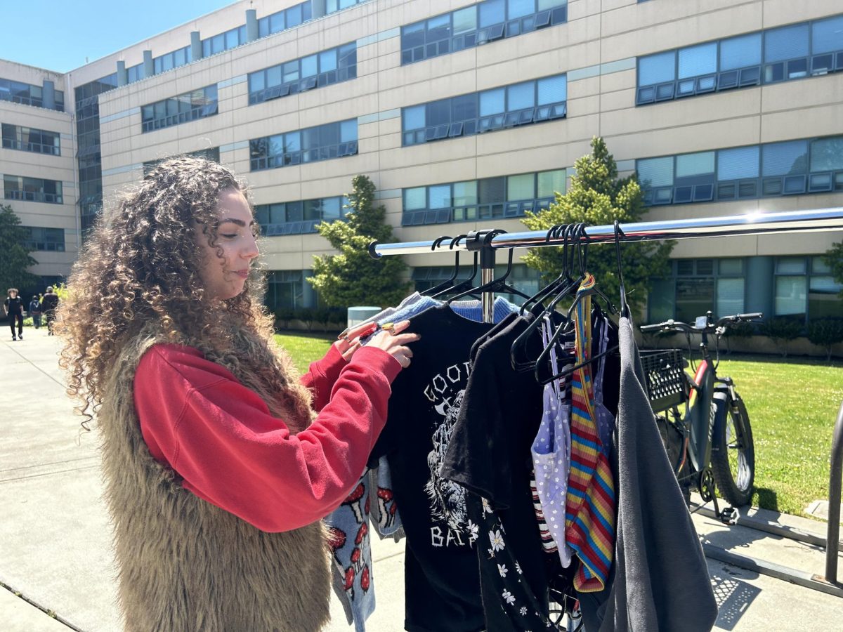 Elyse Tamturk, a graphic design major at San Francisco State University, looks through old clothes she planned on selling at her pop-up in front of the Humanities Building on May 7, 2024. (Natalie Metcalf / Golden Gate Xpress) 