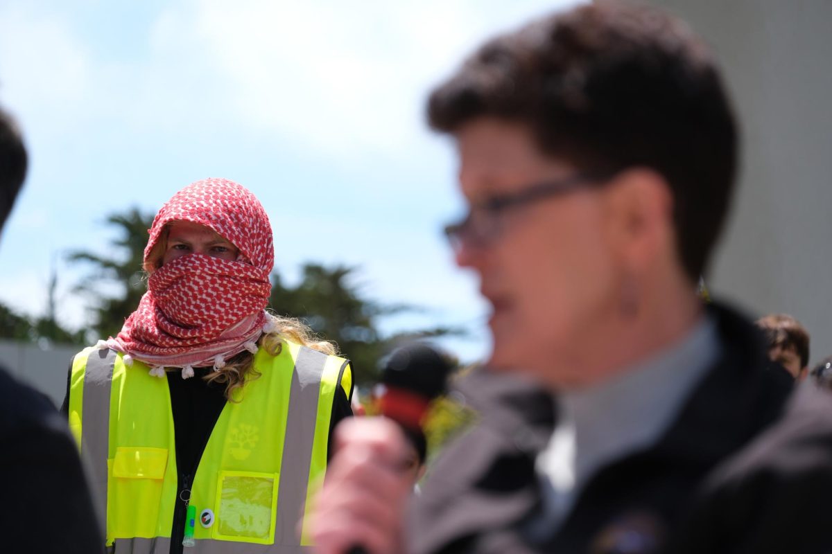 A member of Students For Gaza watches University President Lynn Mahoney speak during their opening bargaining meeting in Malcolm X Plaza on May 6, 2024. The group developed a large presence on campus last semester after holding various demonstrations in support of Palestine and a modified investment strategy by the university. (Andrew Fogel / Golden Gate Xpress)