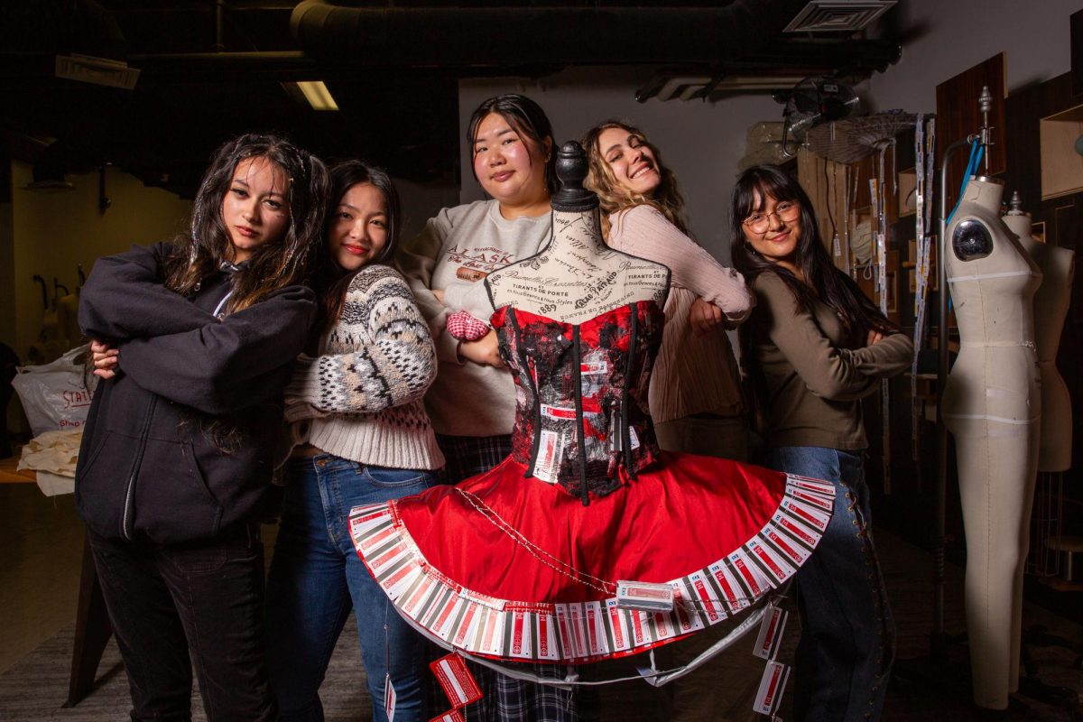 (L-R) Apparel design and merchandising students Genesis Saenz, Ashley Miura, Qiuyan Lin, Siena Dawkins and Antoinette Montano pose with a dress they designed using old BART tickets in Burk Hall on Tuesday, Sept. 10, 2024. The dress was made for Project Doneway: A Farewell to BART Paper Tickets, a fashion show that will be held on Saturday at Rockridge BART.  (Dan Hernandez / Golden Gate Xpress)