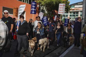 Protesters picket against rideshare denials to blind people with guide dogs, outside Lyft headquarters on Tuesday, Oct. 15, 2024. They protested outside Uber headquarters earlier. (Neal Wong / Golden Gate Xpress)