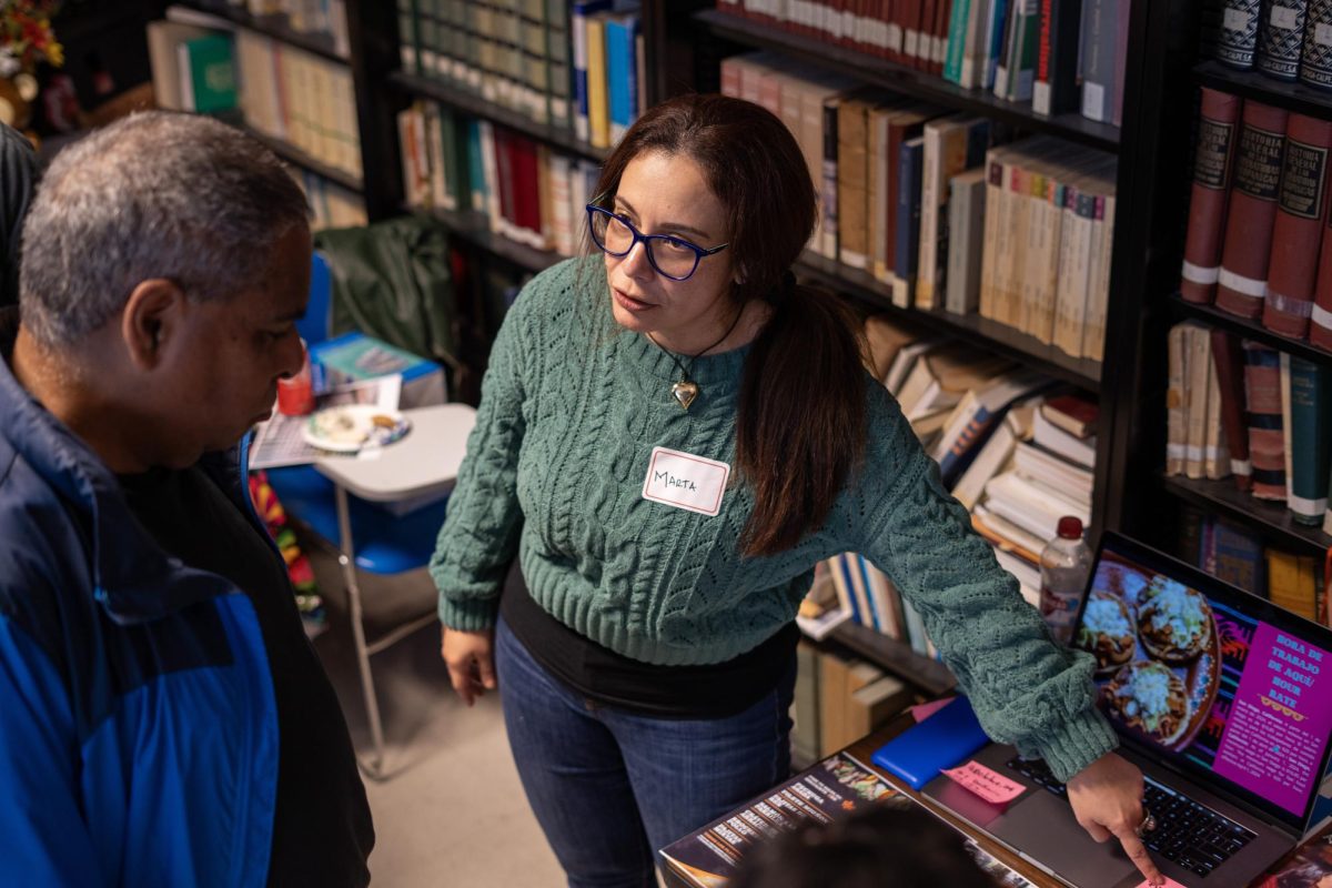 Marta Dugarte presenta su proyecto a un asistente durante ‘Ni de Aquí, Ni de Allá’ en la sala 473 del edificio de las Humanidades el 9 de octubre. (Sean Young / Golden Gate Xpress)