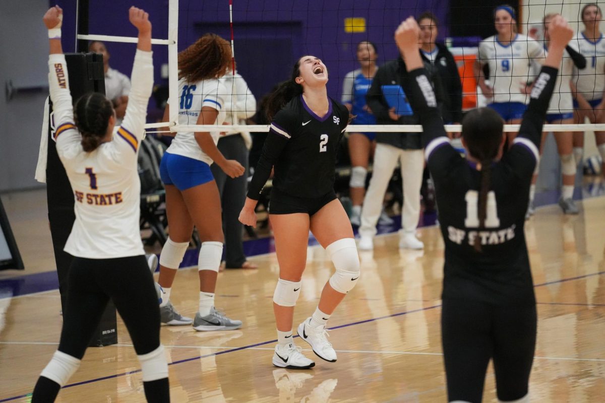 Izzy Issak (center), a redshirt senior outside hitter for San Francisco State University women’s volleyball team, celebrates after a momentum building block against Chaminade University of Honolulu on Sunday, Sept. 29, 2024. (Andrew Fogel / Golden Gate Xpress)