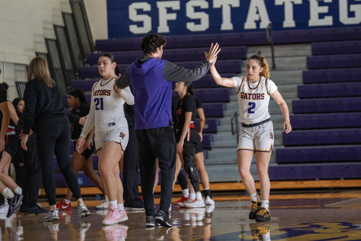 Nyana Asiasi (21) and Alexsandra “Alley” Alvarado (2) high-five Assistant Coach Dante Henley during a timeout against the Pioneers from California State University, East Bay on Saturday, Nov. 30, 2024. (Sean Young / Golden Gate Xpress)