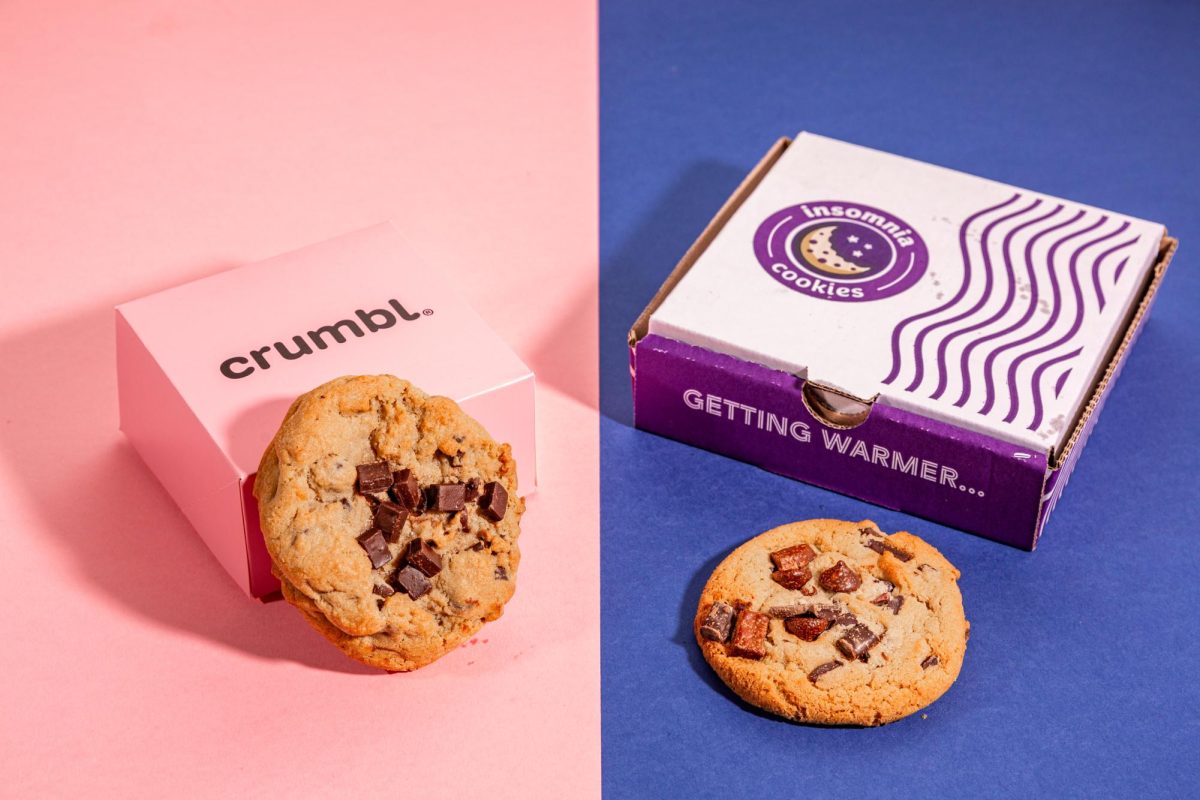 Two chocolate chip cookies, one by Crumbl Cookies (left) and the other by Insomnia Cookies, are staged with their respective boxes. (Dan Hernandez / Golden Gate Xpress)