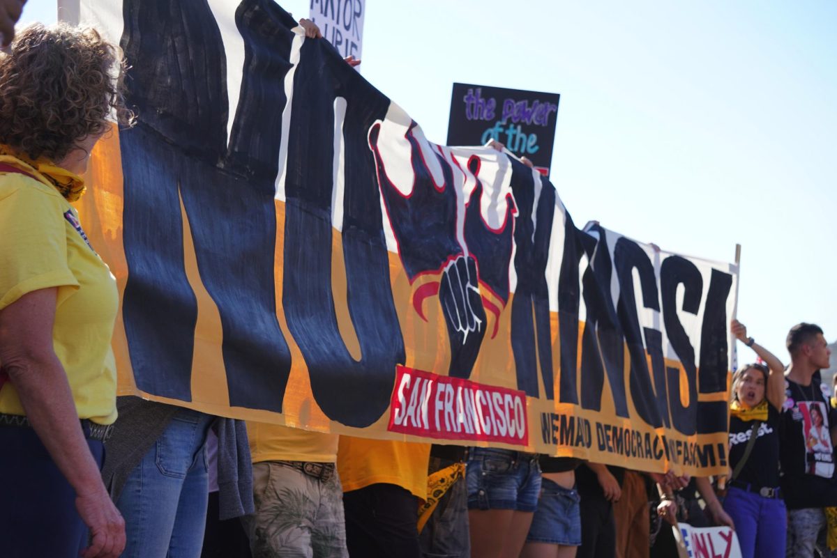 San Francisco “No Kings” protesters holding up a banner reading “No Kings!” in front of the main stage at Civic Center Plaza on Oct. 18, 2025. (Lindsey Hoang / Golden Gate Xpress)