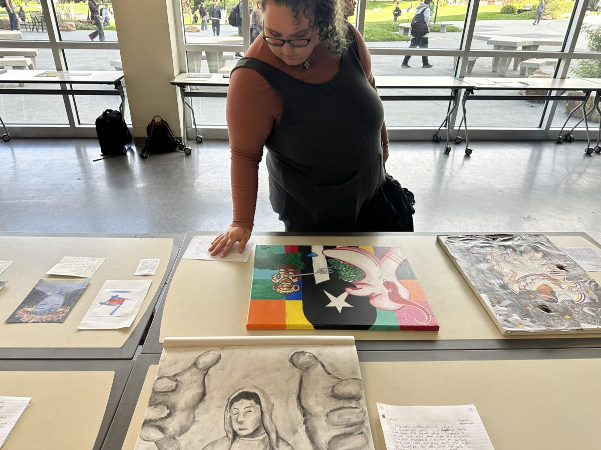 Art history student Carolynne Marshall carefully observes the painting "La Puerta Rico" at the AURA exhibition in the J. Paul Leonard Library on Thursday, Nov. 20, 2025. (Carla Gutierrez special to Golden Gate Xpress) 
