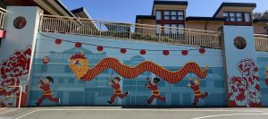 A mural of festival lanterns and children holding a Chinese New Year dragon costume at Alice Fong Yu Alternative School in 2025. (Photo courtesy of Sandra Zhao) 