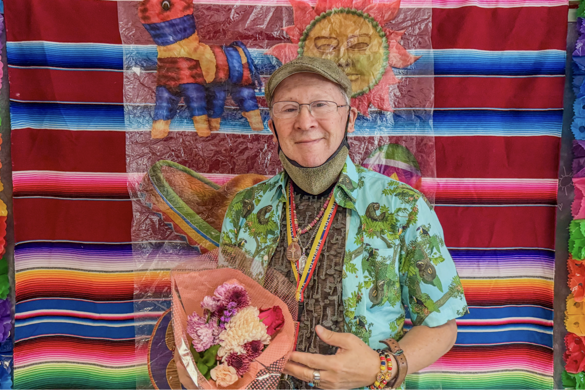 El profesor Gustavo Calderón sostiene un ramo de flores después de impartir su clase de gramática avanzada en su último día de enseñanza antes de su jubilación, en el salón 473 del edificio de Humanidades, el jueves 14 de mayo de 2026. (Carla Gutierrez / Golden Gate Xpress)
