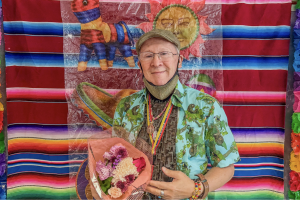 El profesor Gustavo Calderón sostiene un ramo de flores después de impartir su clase de gramática avanzada en su último día de enseñanza antes de su jubilación, en el salón 473 del edificio de Humanidades, el jueves 14 de mayo de 2026. (Carla Gutierrez / Golden Gate Xpress)
